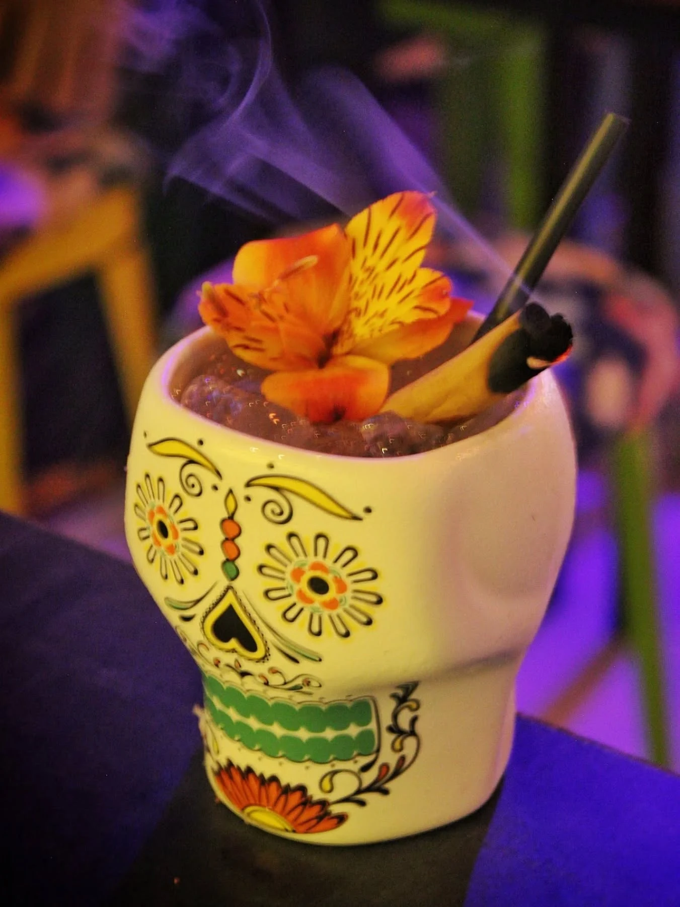 Coctel de autor en vaso de calavera con flor y humo